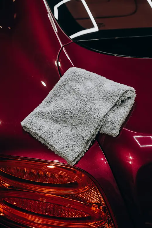 Microfiber cloth on the glossy fender of a deep red car