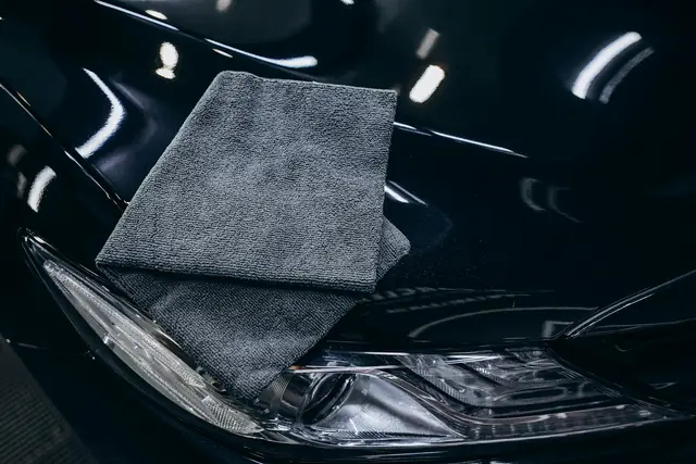 Grey microfiber towel resting on a glossy black hood