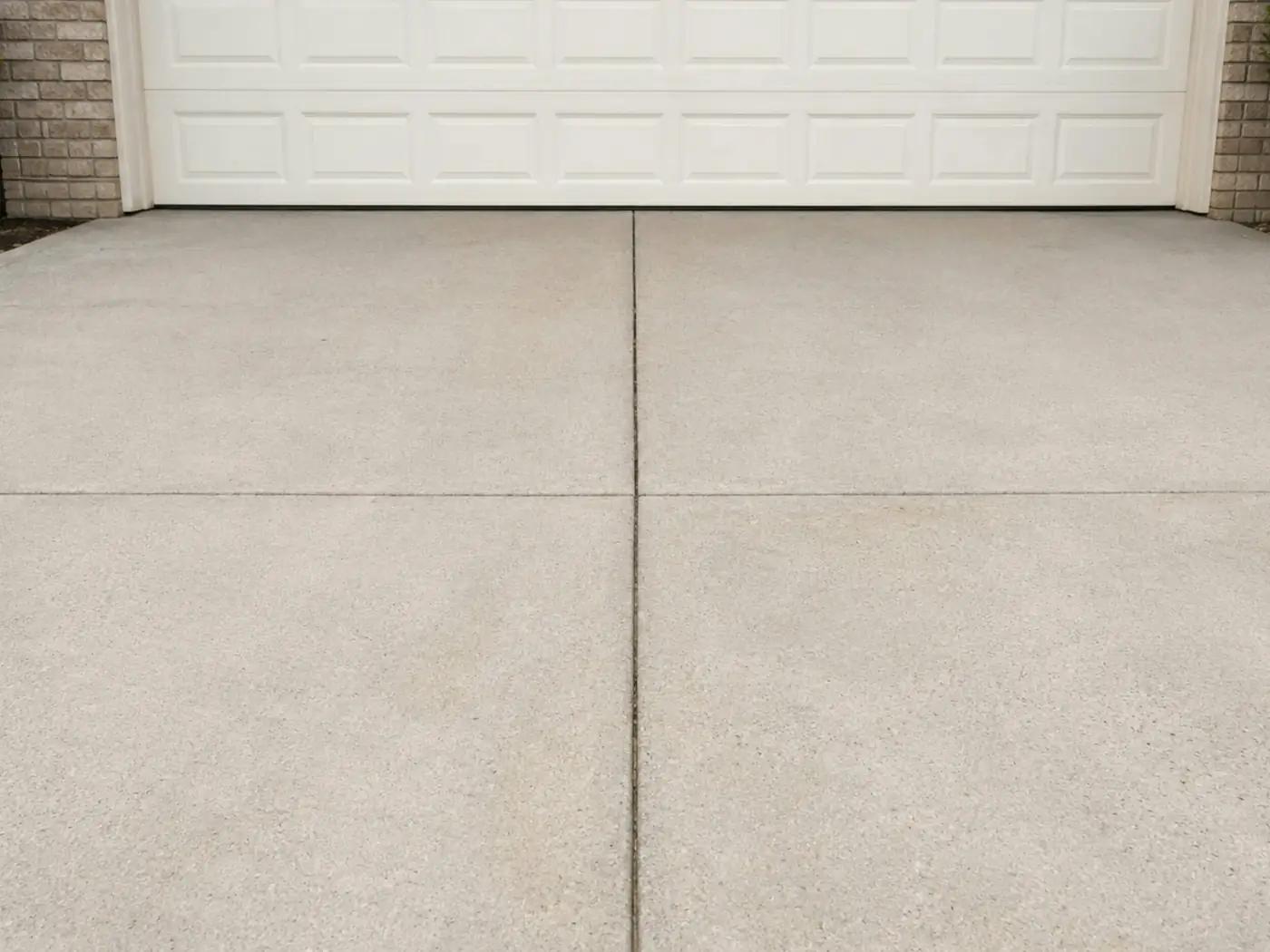 Clean, bright concrete driveway in front of a white garage door