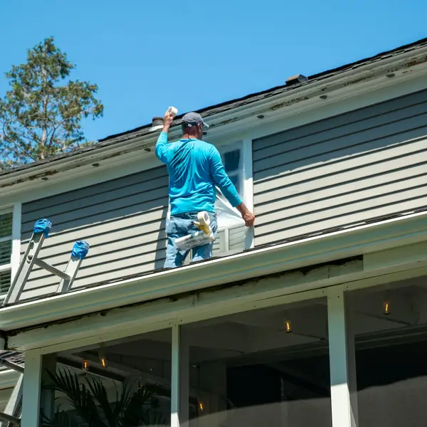 Technician cleaning the upper exterior of a two-story home