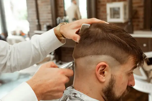 Barber blending a fade with clippers and a comb