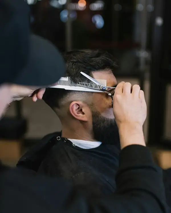 Barber cutting hair over a comb with shears