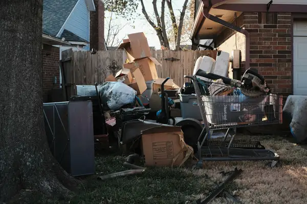 Backyard piled with boxes, a shopping cart and household junk