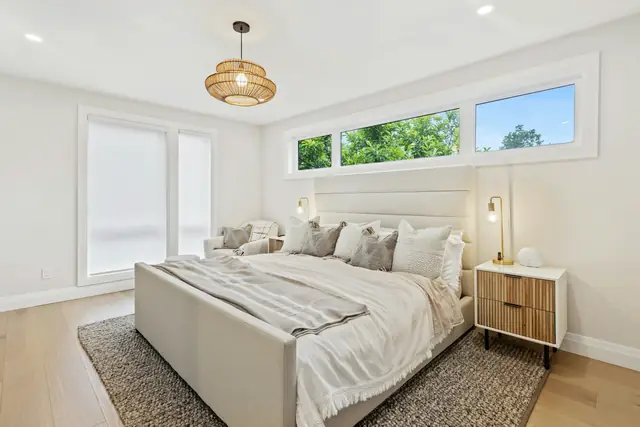 Calm white bedroom with a neatly made bed and wood nightstand