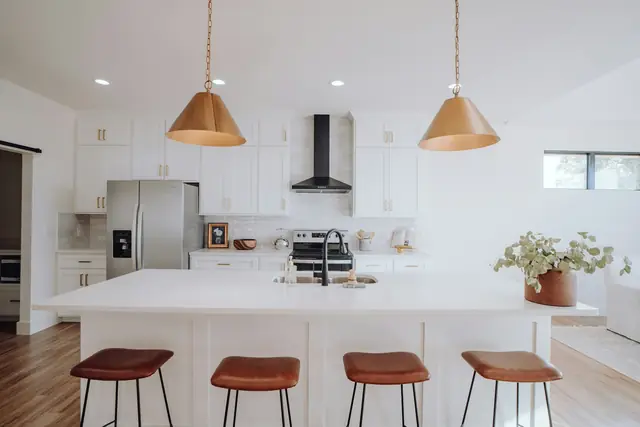 Spotless white kitchen with a large island and leather bar stools