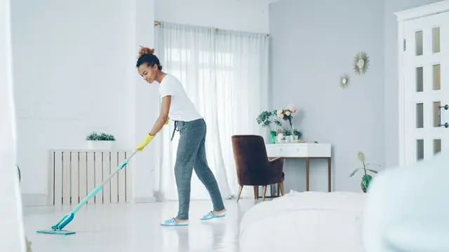 Cleaner mopping the floor of a bright, airy living room