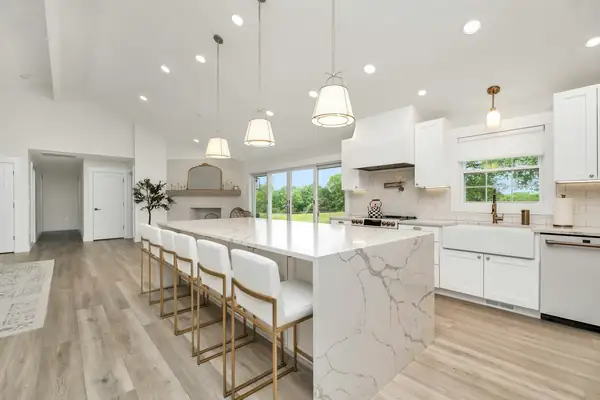 Open kitchen with a marble waterfall island and gold bar stools
