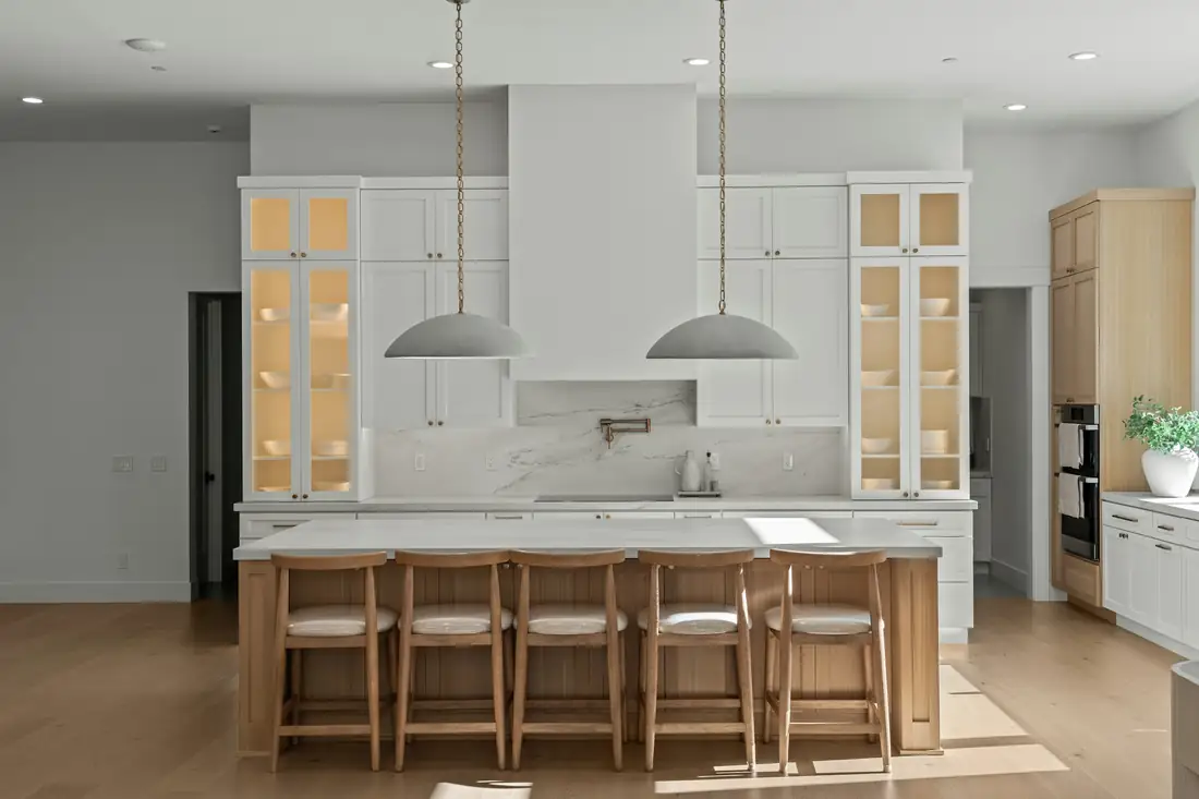 White kitchen with glass-front cabinets and a light oak island